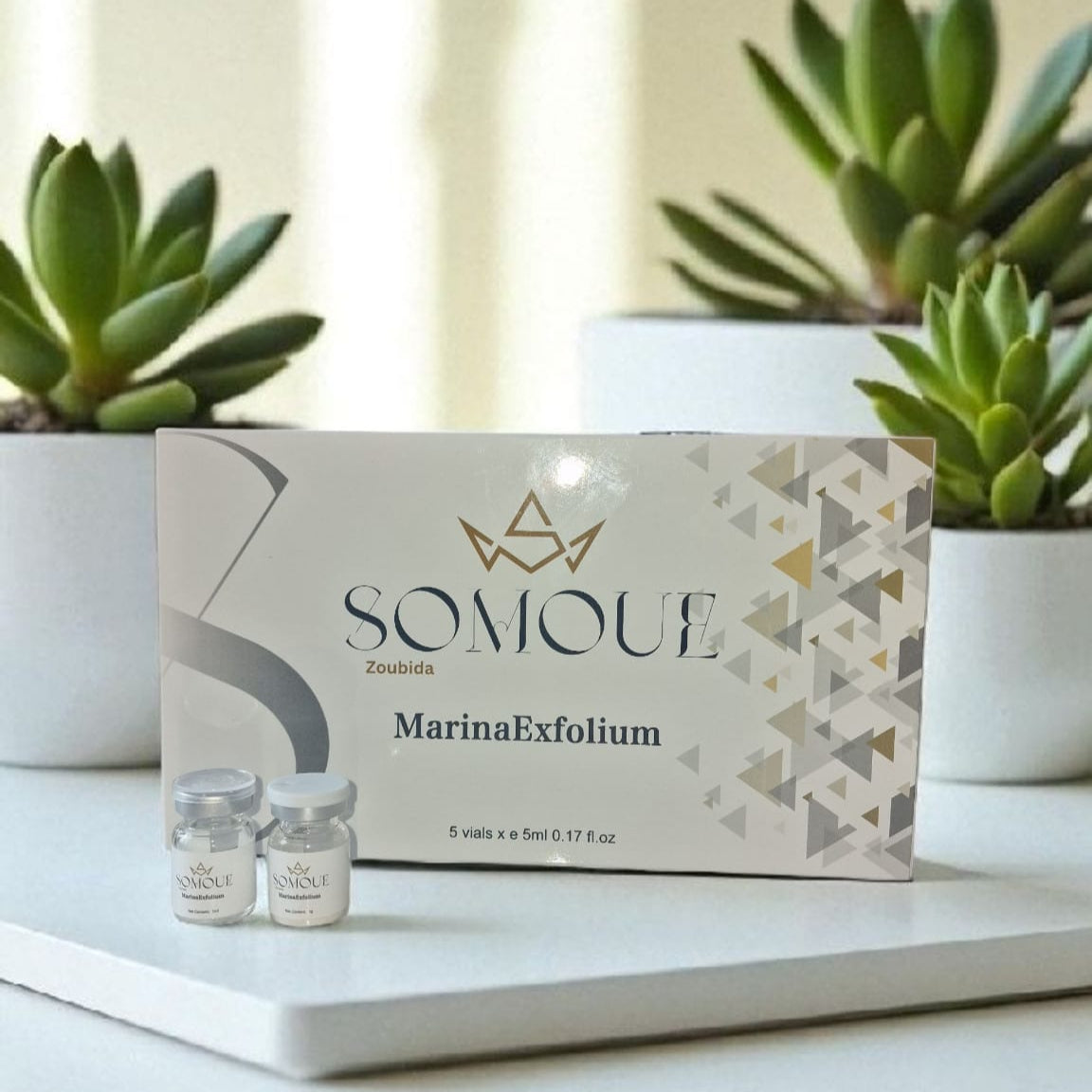 SOMIOUE MarinaExfolium skincare product packaging on a white surface with plants in the background