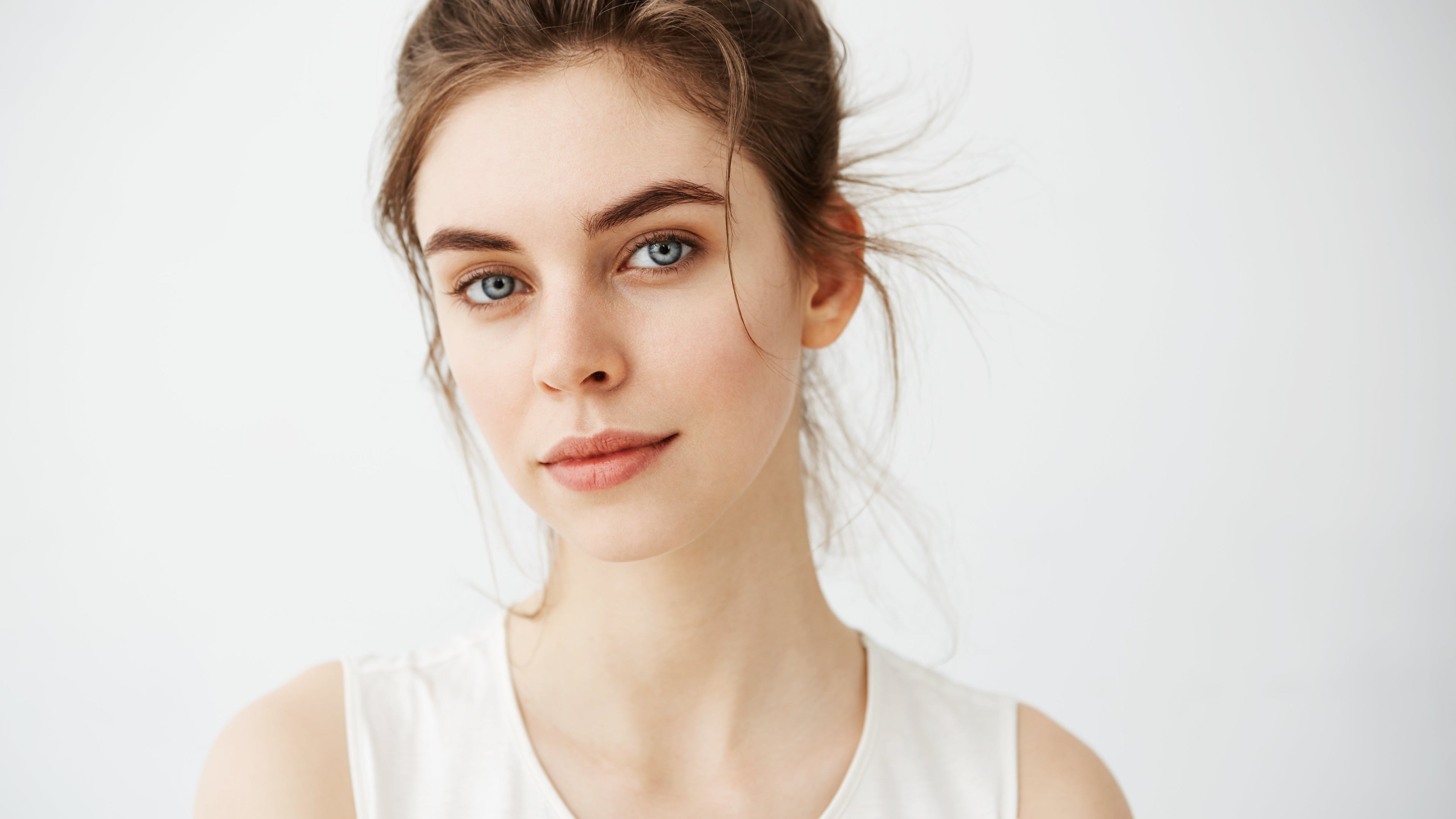 Woman wearing a white sleeveless top against a light background